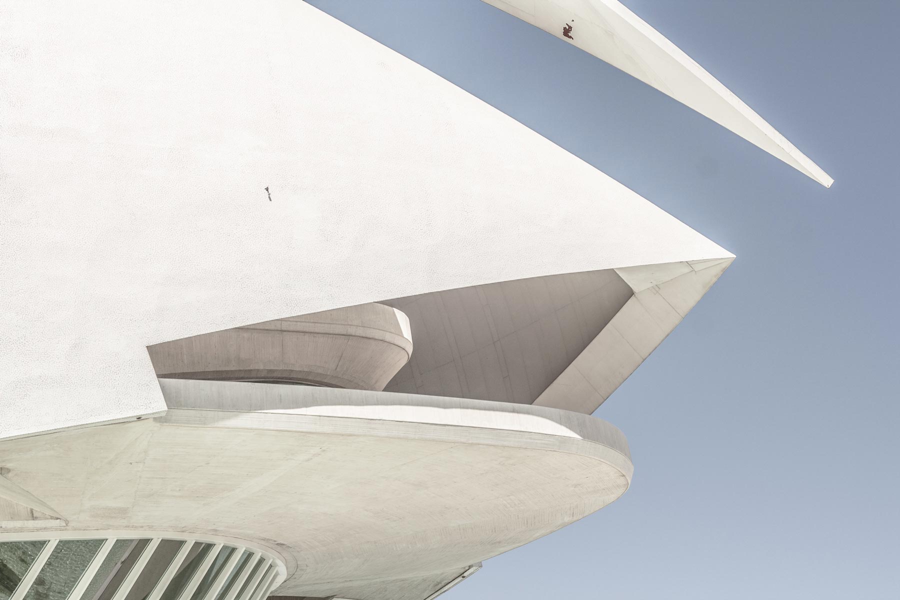 Close-up of the corner of a white, geometric building with both sharp points and round corners.